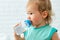 Child holds a plastic water bottle and drinks