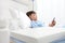 Child in hospital bed using smartphone surfs the internet wearing earphones