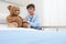 Child in hospital room playing with a stethoscope and a teddy bear imitating doctor