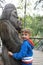 Child hugging wooden sculpture of viking god