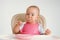 The child independently eats cottage cheese with a spoon while sitting on a chair on a white background