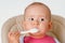 The child independently eats cottage cheese with a spoon sitting on a chair on a white background, close up