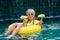 Child with inflatable toy ring float in swimming pool. Little Girl with pineapple lying on a rubber ring in the pool of tropical