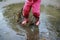 Child jumps in a dirty puddle