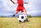 Child, kicking and soccer ball on green grass for sports, training or practice with clouds and blue sky. Closeup of