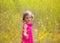 Child kid girl in spring yellow flowers field and pink dress