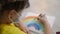 child kid in a mask draws a rainbow at home. stay at home coronavirus concept. girl kid in protective mask draws a