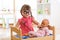 Child in kindergarten. Kid in nursery school. Little girl preschooler playing doctor with doll.