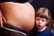 Child kissing belly of pregnant woman