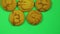 A child lays out caramelized cookies with currency signs on a green background. Time laps.