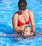 Child learn to swim in swimming pool with teacher.