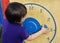Child learning time with wooden clock at  play ground in summer, Kid boy learning to tell time, kid hands, Concept of learning by