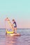 Child learning to windsurf at sunset