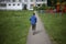 The child leaves along the road. The boy goes for a walk alone in the summer. Child from the back.