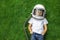 child lies on the grass wearing an astronaut`s helmet and dreams of great achievements