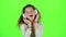 Child listens to the music in the headphones. Green screen