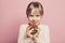 Child llittle girl holding donut on pastel pink background