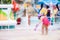 Child looking down fountain. She turned her back to camera. Asian Girl wear red swimming suit and hold purple swimming goggles in
