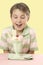 Child looking at an ice cream sundae on a table.