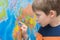The child looks at the map of the world with concentration, enthusiasm. Close-up, horizontal photo. Idea - preschool
