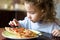 Child looks at pizza on table. Three years old kid is going to eat by himself