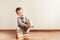 Child with lots of independence sitting on the floor putting on his socks with an expression of effort