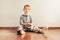 Child with lots of independence sitting on the floor putting on his socks with an expression of effort