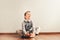 Child with lots of independence sitting on the floor putting on his socks with an expression of effort