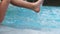 Child lowers his feet into the pool. The girl dangles in the water.