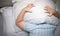 Child lying in bed covering head with pillow