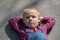 Child lying on the floor on back, looking long way off. thoughtful boy portrait lying on crossed arms look into the distance