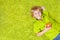 Child lying on the green carpet, holding apple