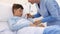 Child lying in the hospital bed, nurse with thermometer measures the temperature of the fever