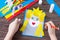 A child is making a birthday greeting card of a little princess girl, draws details, a paper craft.