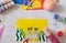 Child making card with Easter bunnies toys from colorful paper and placticine. Handmade. Project of children`s creativity,