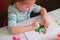 Child making homemade greeting card. little girl making vase with flowers from paper and clay, plasticine as gift for Mothers day