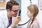 Child male optometrist examines eyesight of little girl