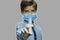 Child in medical mask holding syringe.