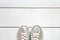 Child metallic silver sneakers on white wood board background texture with copy space. White sneakers for girls. Top view