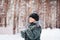 Child in mittens stretches her hand to catch falling snowflakes