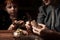 Child with mom peels potatoes on a dark background. A woman teaches her son to peel potatoes