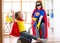 Child and mommy dressed as superheroes using vacuum cleaner in room. Family - woman and kid daughter have a fun while