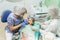 Child with a mother at a dentist`s reception. The doctor works with an assistant. There is an operation to fill the