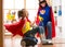 Child and mother dressed as superheroes using vacuum cleaner in room. Family middle-aged woman and daughter have a fun