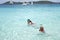 Child and mother snorkeling in tropical ocean