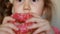 Child mouth bites rose donut. Closeup baby girl eating doughnut with glase. Delicious, sweet, sweettooth.