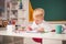 Child near chalkboard in school classroom. School kids against green chalkboard. Pupil learning letters and numbers.