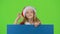 Child in New Year`s clothes jumps out from behind the board and shows ok. Green screen