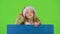 Child in New Year`s clothes jumps out from behind the board and shows ok. Green screen. Slow motion