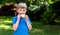 Child, one little girl eating a plain slice of bread with butter in the garden outside, closeup, portrait